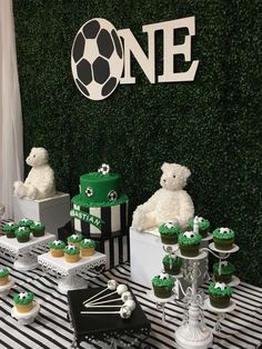 a table topped with cupcakes and cakes covered in green frosted icing