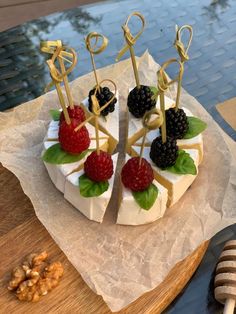 a cake decorated with berries, raspberries and other toppings sits on a piece of wax paper