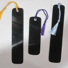 three black bookmarks with tassels on them and one has a yellow cord