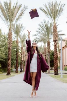 a woman is throwing her graduation cap in the air