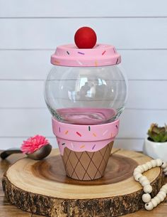 a pink cupcake with sprinkles and a cherry on top sits in front of a glass bowl