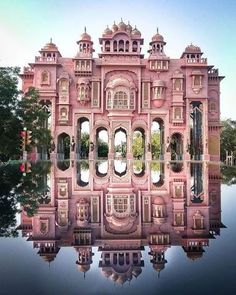 a large pink building sitting on top of a lake