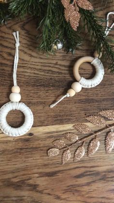 two wooden beaded rings on a wood board next to some christmas tree branches and ornaments