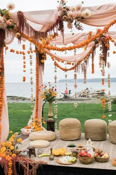 a table with flowers and fruit on it near the ocean in front of an outdoor seating area