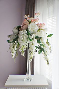 a vase filled with white and pink flowers sitting on top of a table next to a radiator