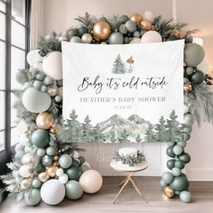 a baby shower sign surrounded by balloons and greenery