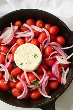 tomatoes, onions and cheese are being cooked in a skillet