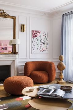 an orange chair and ottoman in a white room with paintings on the wall behind it