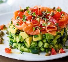 a white plate topped with cucumber, tomatoes and other vegtables