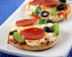 two mini pizzas with pepperoni, black olives and jalapenos