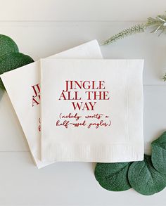 two napkins with words on them sitting next to some green leaves and greenery