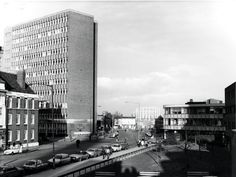 an old black and white photo of cars on the street in front of tall buildings