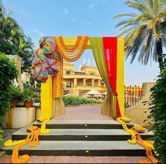 an outdoor ceremony with yellow and red draping on the steps leading to it