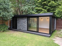 a black and white building in the middle of a yard with windows on it's side