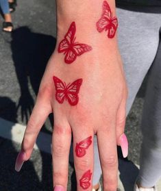 a woman's hand with red butterflies painted on it