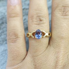 An oval cut violet tanzanite is the focal point for this lovely ring. The beautiful tanzanite is set in 14k yellow gold with an accenting braided infinity criss-cross band. Metal: 14K Yellow Gold Tanzanite: 7 x 5 MM Size: 8.5 If you have any questions about this product or if we can help you with any of our other products please contact us. Each piece of our jewelry has been identified by our Graduate Diamond Grader certified by the Gemological Institute of America (GIA). For more information ab Gold Tanzanite Birthstone Ring, Formal Oval Tanzanite Birthstone Ring, Gold Birthstone Ring With Tanzanite, Elegant Oval Tanzanite Birthstone Ring, Gold Tanzanite Oval Ring, Tanzanite Oval Birthstone Promise Ring, Oval Tanzanite Birthstone Ring With Accent Stones, Oval Tanzanite Birthstone Promise Ring, Gold Tanzanite Birthstone Promise Ring