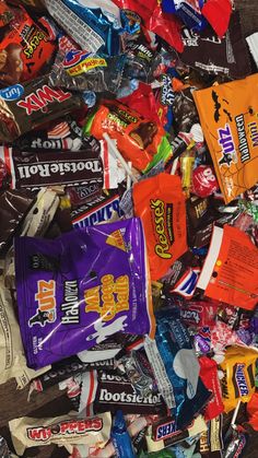 a pile of assorted candy bars on top of a wooden table next to each other