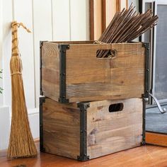 a wooden crate sitting on top of a hard wood floor next to a broom and potted plant