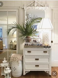 a white dresser with a mirror and potted plant on it in a living room