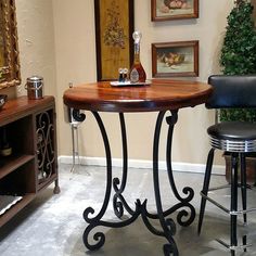 a small table with two stools in front of it and pictures on the wall