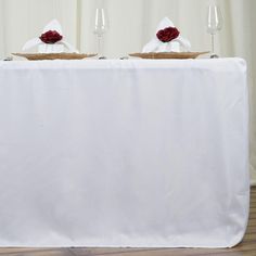 two wine glasses sitting on top of a table covered in white cloths and napkins