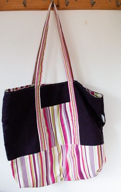 a multicolored striped bag hanging on a wall with hooks and clothes pegs