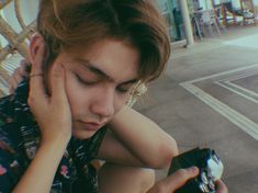 a woman holding a cell phone to her ear while sitting on a bench in front of a building