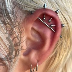 a close up of a person wearing ear piercings with spikes on their ears and behind the ear