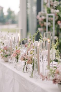 a long table with many vases and candles on it, all filled with flowers