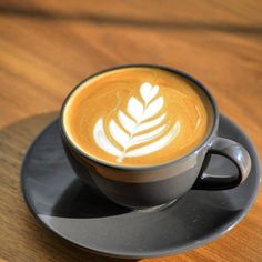 a cappuccino on a saucer with a leaf design in the foam