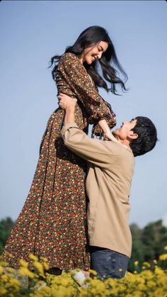 a man is holding the back of a woman's head in a flower field