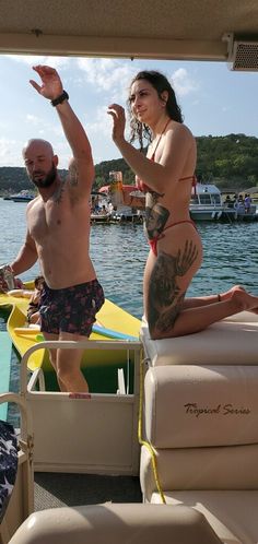 a man and woman on a boat in the water with one holding up her hand