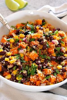 a white bowl filled with black beans, corn and cilantro next to a lime wedge