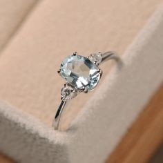 a ring with an aqua blue topaz surrounded by three white diamonds in a box