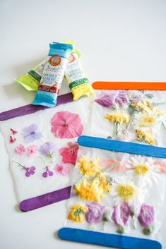 three craft kits with flowers on them sitting next to some glue sticks and one is made out of paper