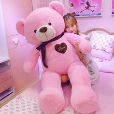 a girl is holding a large pink teddy bear