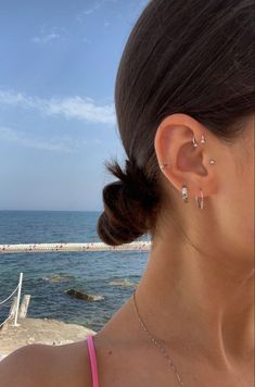 a woman with ear piercings looking out at the ocean