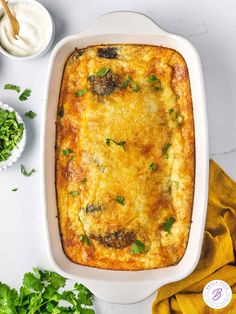 a casserole dish with meat and cheese in it on a white surface next to some parsley