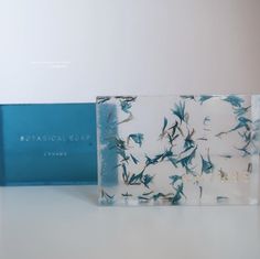 two glass blocks with blue flowers on them sitting next to each other in front of a white wall