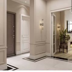 the interior of a house with white walls and wood flooring, two planters on either side of the door