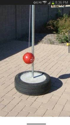 a tire swing with a red ball on it in the middle of a brick walkway