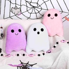 three stuffed ghost pillows sitting on top of a bed