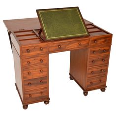 an antique wooden desk with drawers and a green leather pad on it's top