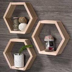 three wooden hexagonal shelves with plants and yarns on them, hanging from the wall