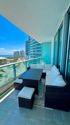 a balcony with wicker furniture overlooking the ocean and cityscape in the background