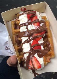 a waffle with strawberries and chocolate drizzled on top in a box