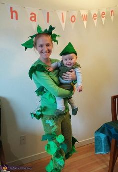 a woman holding a baby in her arms while standing next to a man dressed as the tinkerbell