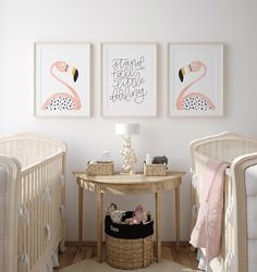 a baby's room with two flamingos on the wall and a table in front of them