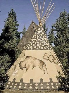 a teepee with bears painted on it in front of some trees and blue sky