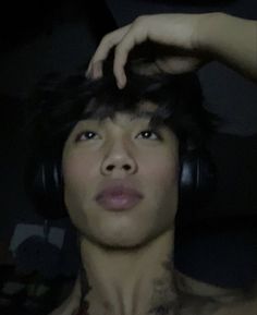 a shirtless man with headphones on is looking up at the camera while holding his hand to his ear